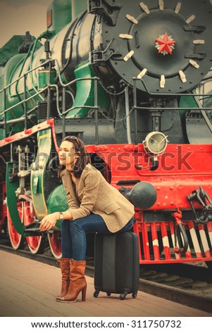 beautiful middle-aged woman sitting on a suitcase and waiting for a retro journey. instagram image filter retro style