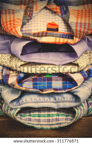 stack of colored cotton shirts on a wooden shelf in a clothes store. instagram image filter retro style