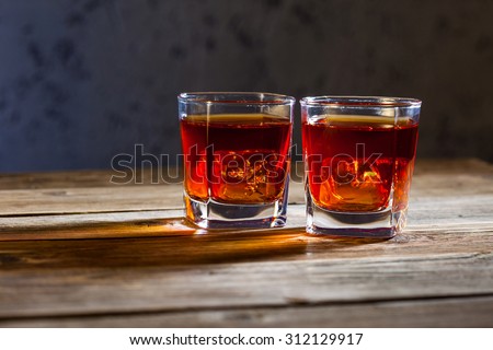 two glasses of old whiskey on the aged wooden textured surface