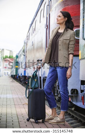 beautiful middle-aged woman with luggage rides on the retro train in the railway travel