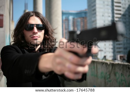 young man with gun in image of the killer in style of the italian film about mafia