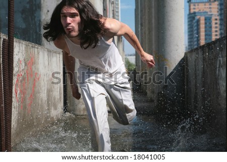 man with long hair running  on the water  in wet white cloth