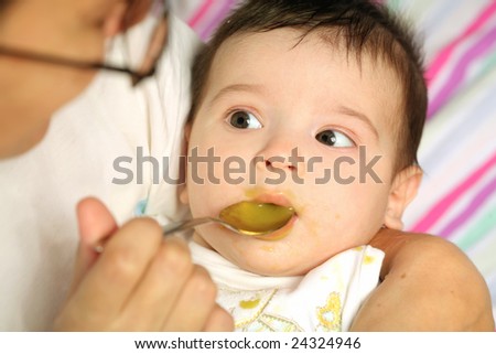 the infant eats the puree by small spoon