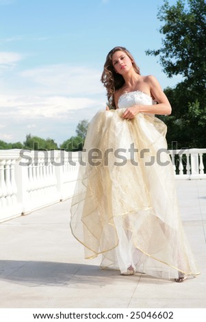 beautiful bride in golden dress under blue sky