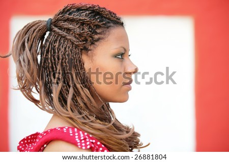 portrait of the girl with exotic hairstyle in profile on the white-red background