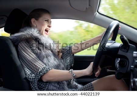 beautiful young woman yells and drive a car