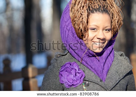 Portrait of a smiling young black woman with purple scarf and flower