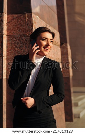 Laughing business woman talking by mobile outdoor