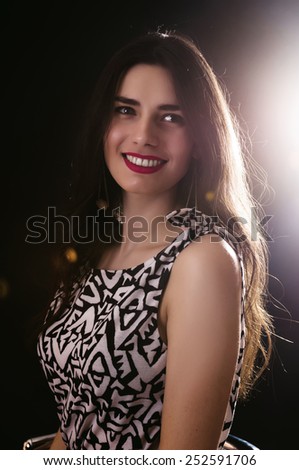 Portrait of beautiful woman on dark background with back lighting