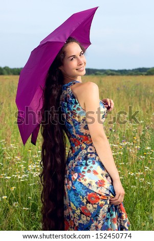 Happy young beautiful woman with color umbrella in field