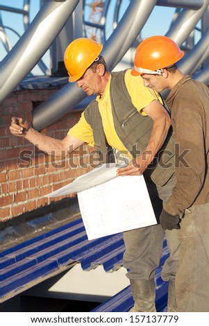 Industrial workers with blue print during construction works