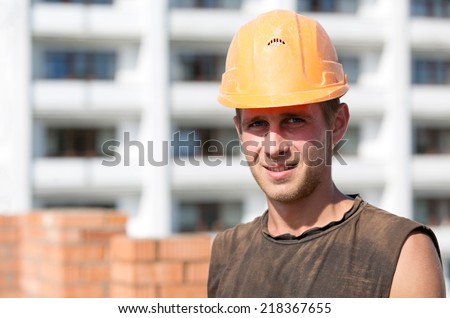 Positive builder man worker with hard hat at construction site background