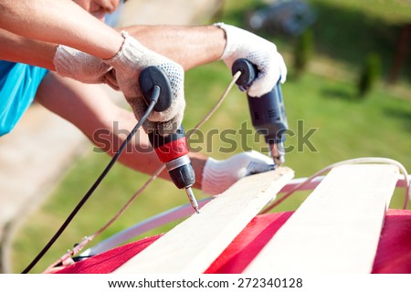 Construction man workers drilling and screwing wood during roofing works