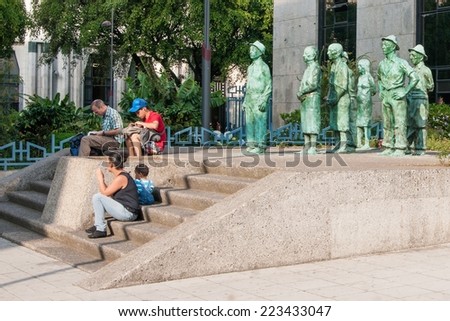 SAN JOSE, COSTA RICA - JANUARY 16, 2013: Everyday people sitting in front of everyday \'Tico\' sculptures in San Jose, Costa Rica on Jan. 16, 2013 in San Jose, Costa Rica (Central America)