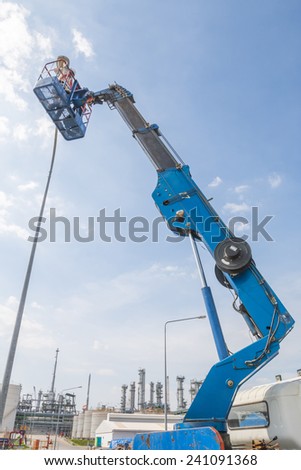 RAYONG , THAILAND , DECEMBER 26 - 2014 ; Electrical technician repairing street light by boom lift in industrial Plant at Rayong, Thailand