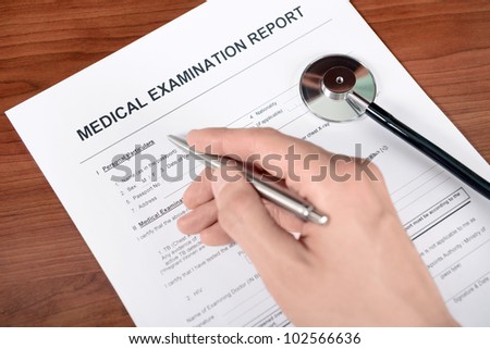 Doctor fills out blank medical report form.
