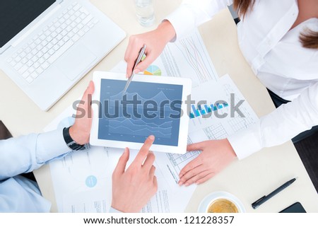 Businessman and businesswoman analyzing financial report on a modern digital tablet. Top view shot.