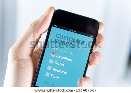 Men\'s hand holding modern mobile phone with customer service survey form on a screen. Red tick on excellent choice showing customer satisfaction.