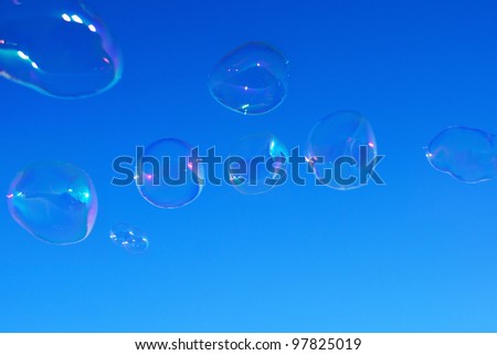 Real natural shaped soap bubbles over clear blue sky. Useful for background