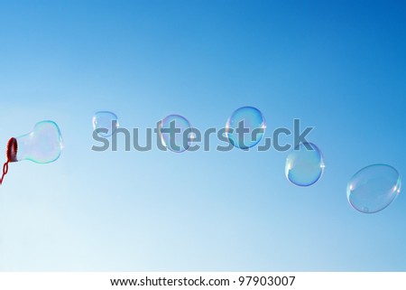 Photo of natural shaped soap bubbles over clear blue sky