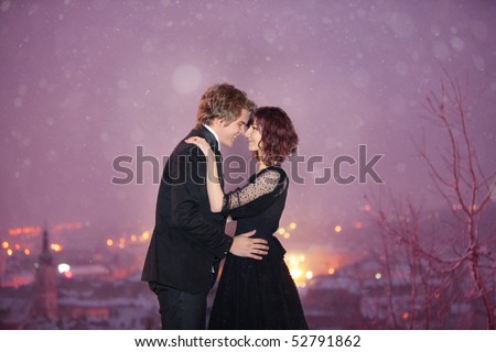 Profile of Romantic Couple smiling looking into each others eyes against the city at night on Valentineâ??s Day