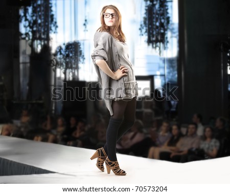 Fashion show with redhead fashion model posing in high hills black tights gray skirt and shirt over