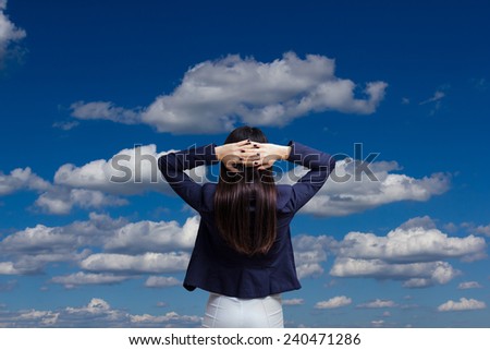 Business woman looking at the sky and holding both hands at the back of the head