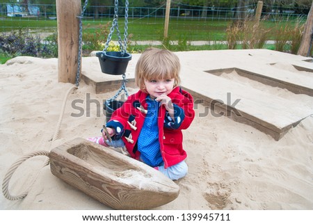 An eighteen month old baby girl playing in the sandpit.