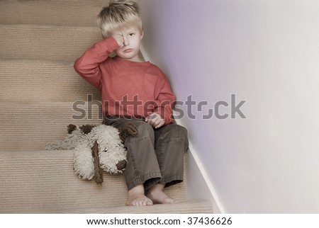 Upset little boy sitting on the stairs.
