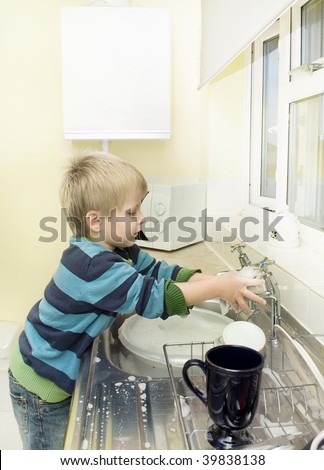 Child plays with soap and water at the kitchen sink.