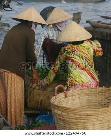 Three Vietnamese fisher women go over their catch on the Mekong River