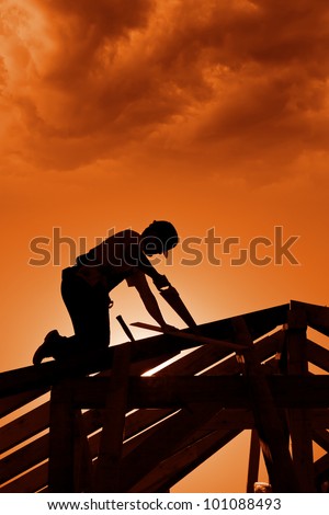Stormy sunset on construction site with carpenter working