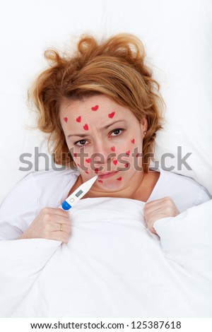 Lovesick woman laying in bed with heart shaped rash spots or pimples