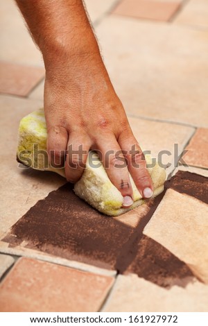 Testing the color of joint on ceramic floor tiling - closeup on hand