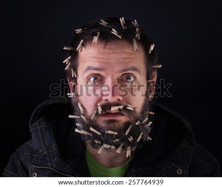 Barely holding it together - stressful bearded man with cloths-pegs holding his head