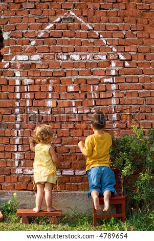 Two children drawing fantasy home on a brick wall - real estate concept