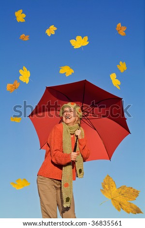 Happy autumn woman with red umbrella under clear blue sky and falling leaves - warm afternoon light