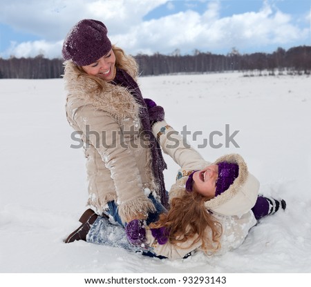 Woman and little girl having fun in the snow on a beautiful winter day