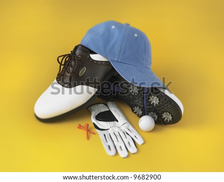 Stylized pile of golf basic golf gear on yellow background.  Shot with a little selective focus.