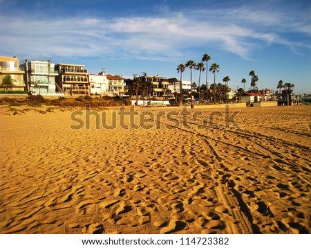 Sandy beach with palm trees and large vacation homes at sunset