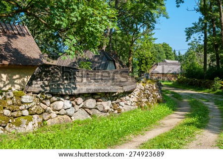Mossy stone fence and old boat as decoration. Koguva village, Saaremaa island, Estonia, Europe