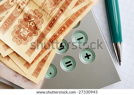 A few banknotes (1 cent) issued by The People\'s Bank of China in 1953 on top of a calculator and a notebook