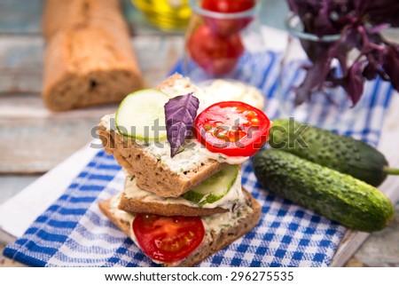 fresh sandwich with tomatoes and cucumber on wooden plate in studio