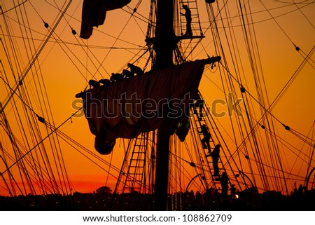 Sailors Take Down the Sails on an Old Ship at Sunset