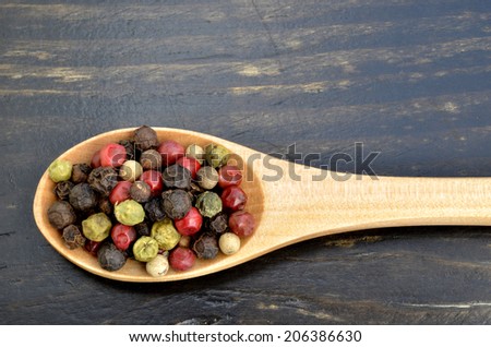 wooden spoon full of mixed peppercorns