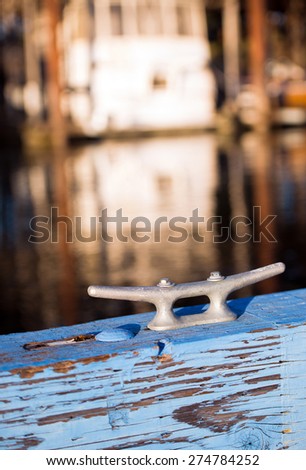Mooring metal bracket on wood painted in blue berth for boats, yachts or marine on the background blurred parking yachts and boats for mooring and floating mounting means.