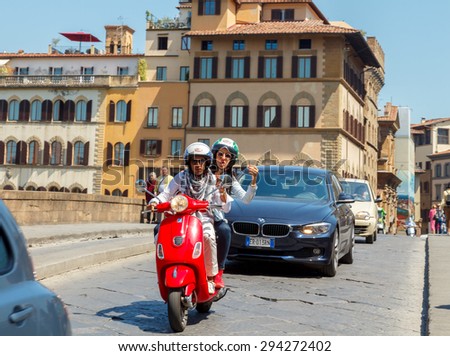 Florence, Italy - May 18, 2015: Couple on a motorcycle is photographed against the backdrop of the city\'s sights on the go.