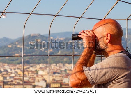 Florence, Italy - May 18, 2015: A man with binoculars examines Florence from the bell tower of the Duomo.