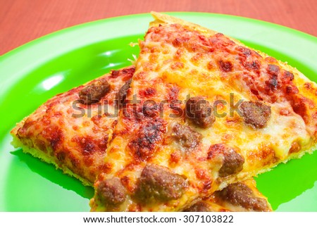 Slice of pizza on round green dish