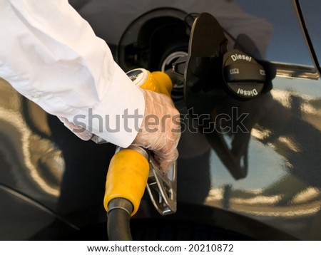 Man wearing protective gloves filling up  his car tank with a yellow nozzle